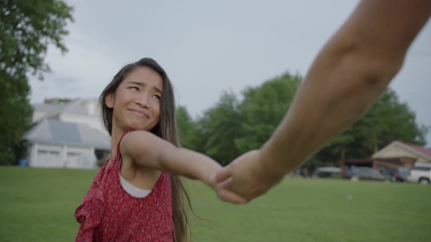 Girl smiles and holds a boys hand pulling him to run with her