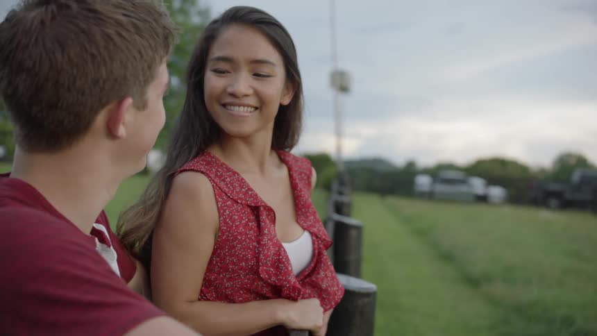 The woman talks with a man by the fence