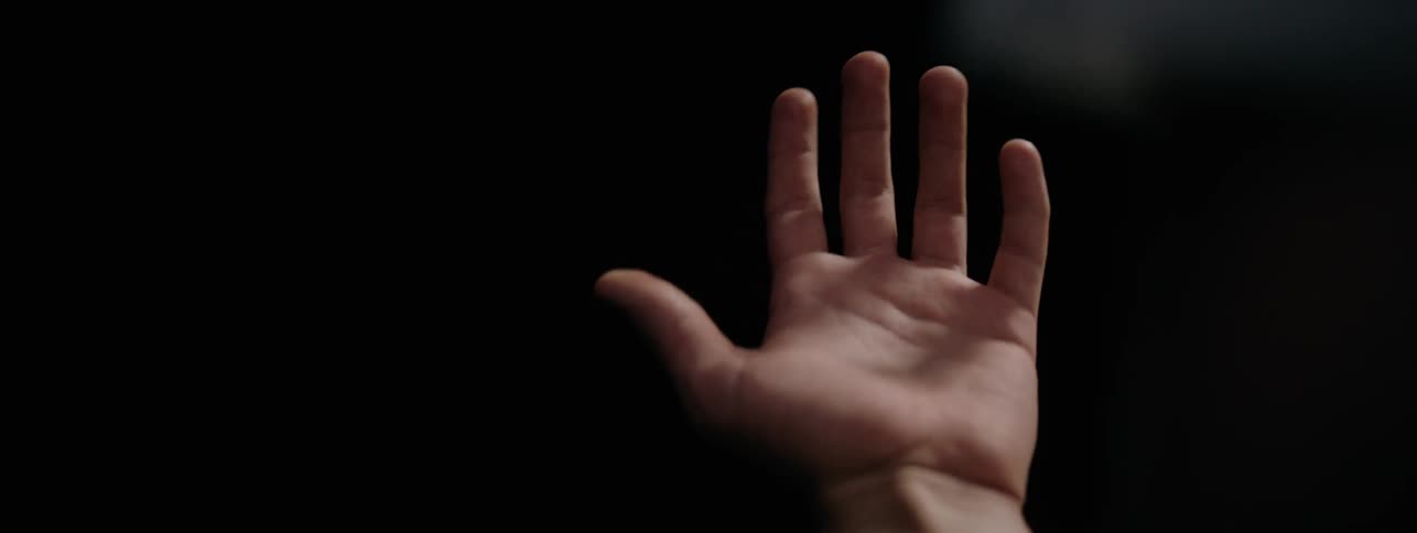 Man holds his palm up and then moves his hand in a dark room