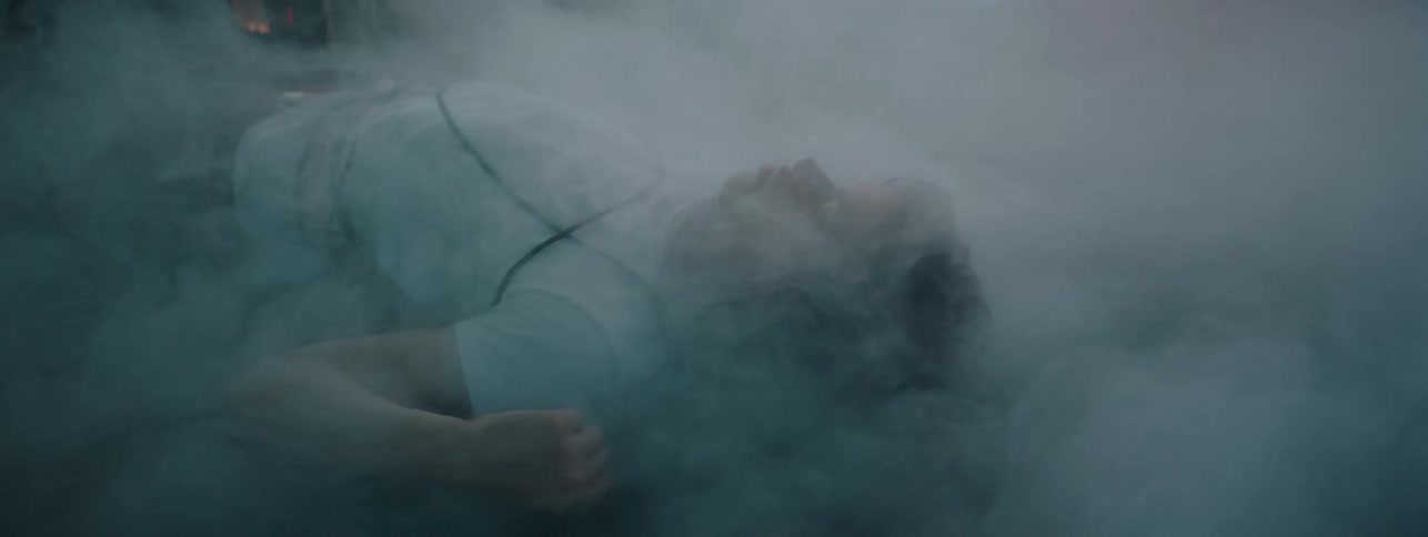 The camera is filming a man on the floor covered in fog