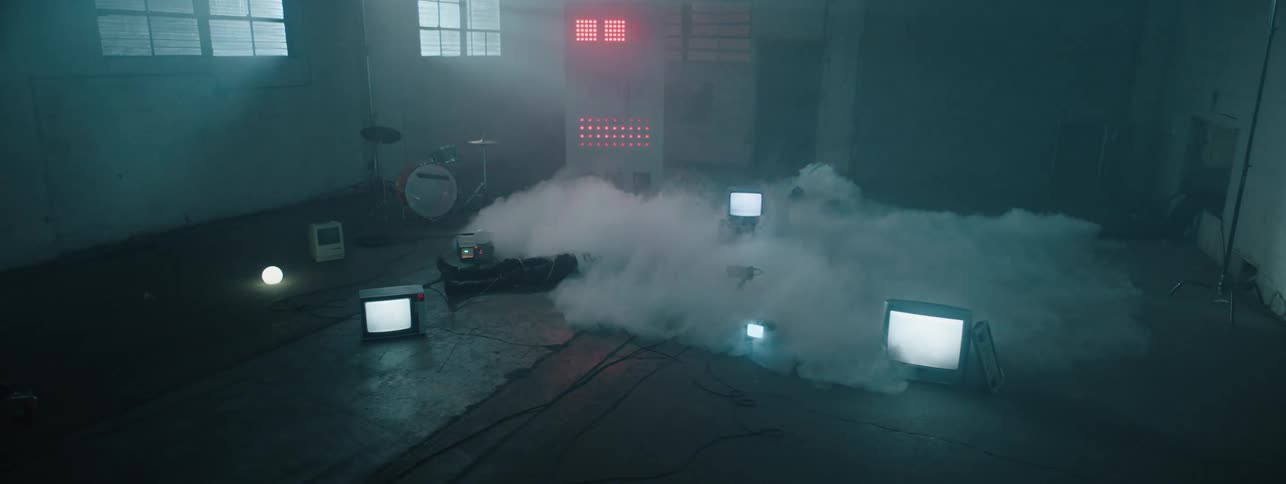 The fog rolls on the ground past the electronics and fallen person