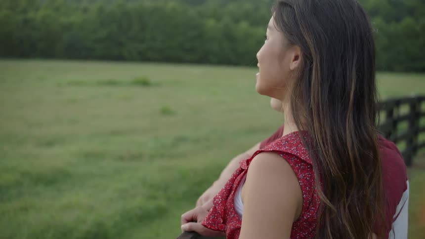 The woman points out over the fence with a man