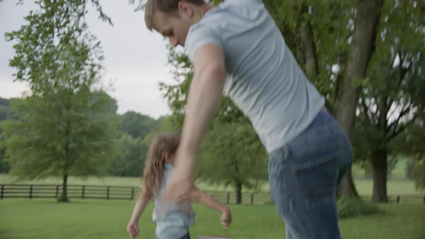 A little girl holding an american flag loses her shoe as she chases her father outside in daylight