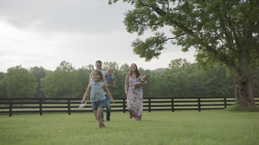 Man and woman walk with their children across a grassy pasture
