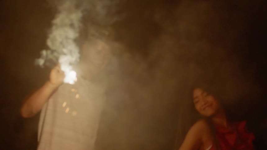 Man and woman hold sparklers as the woman dances around