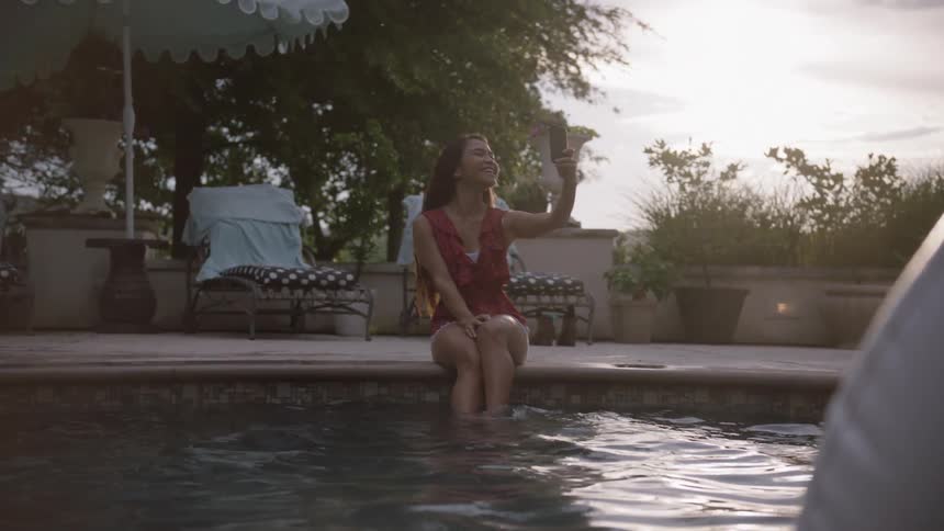 Woman takes a picture of herself with her legs in the pool