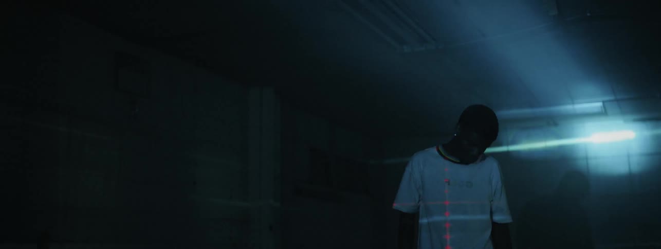 The man is standing in the dark room looking around as the lights flash