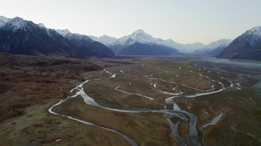 Rivers flow in front of snowy mountains in the wilderness