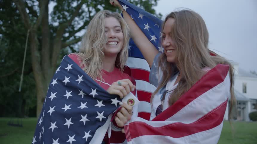 The woman hug each other wrapped in an american flag