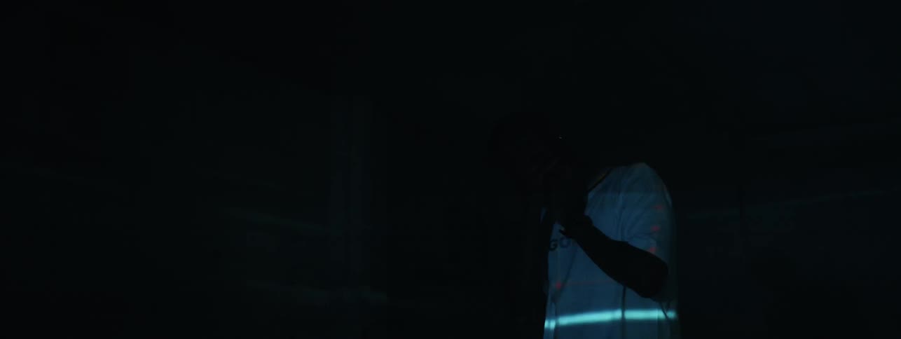 A man standing in a room while lights are flashing is rubbing his face