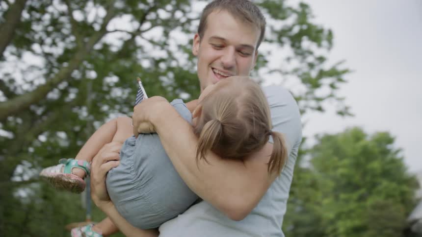Father is holding and playing with toddler daughter outside