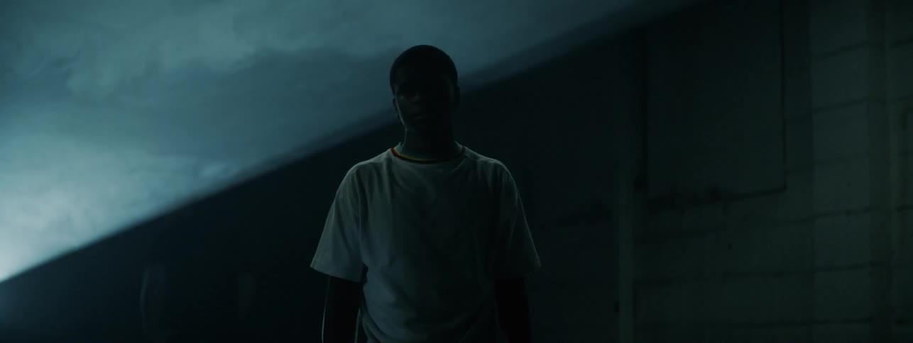 The man stands as a light flashes over him in the dark
