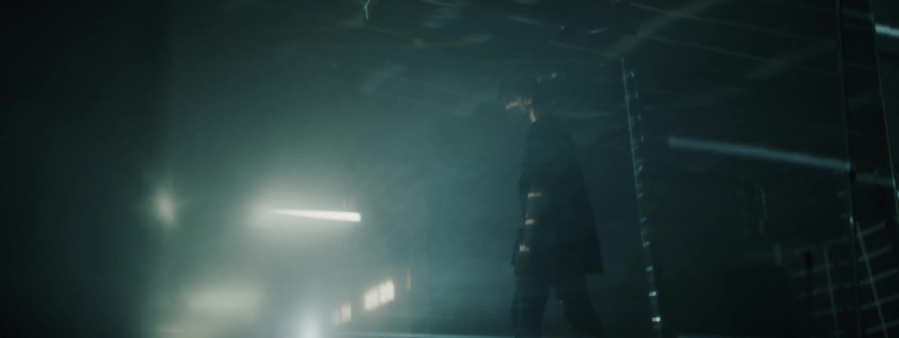 Boy stands in an empty dark room with one light overhead