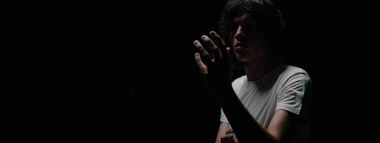 A man looks at his outstretched hand in the dark