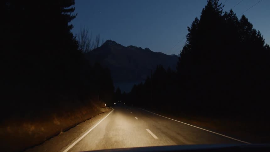 Headlights of car shining on road while traveling at night