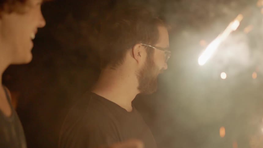 Boys and men hold sparklers in a yard at night