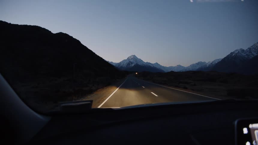 The vehicle is lighting up the road as it travels at dawn