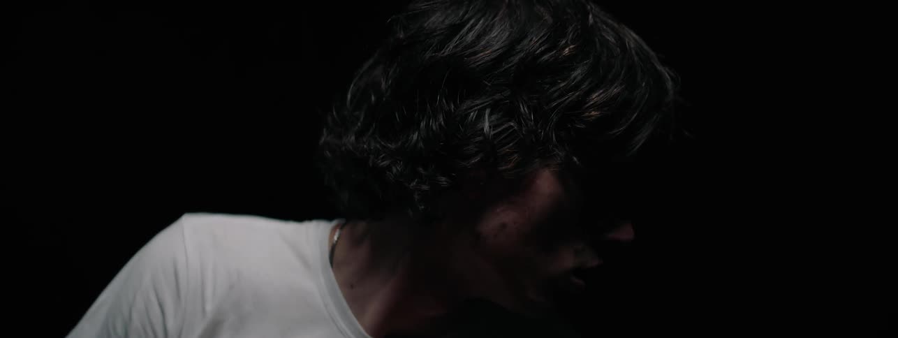 The man is rubbing his hands together in the dark room