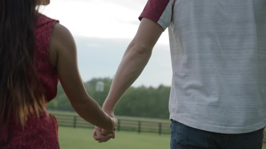 The man and woman hold hands smiling at each other