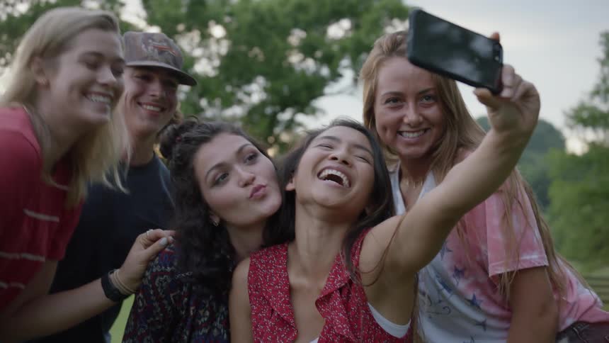 The people pose for a photo from a cell phone being held up