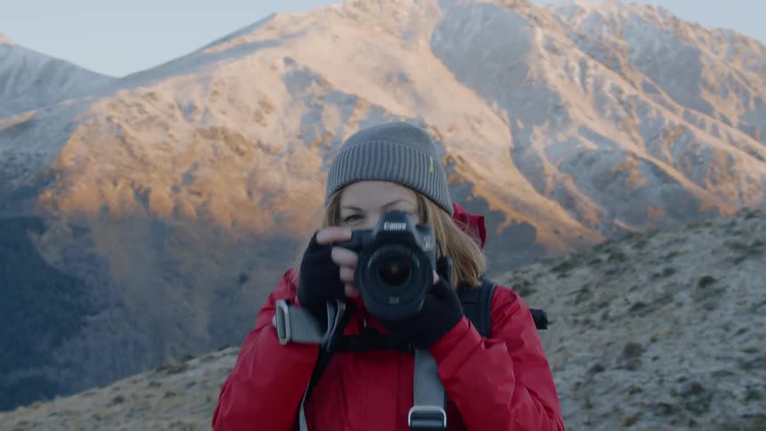 The woman takes photographs on the mountain top