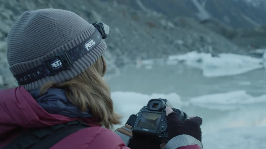 Woman with camera is photographing icy lake