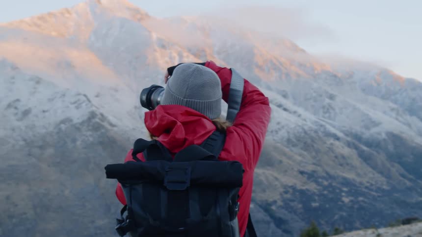 The woman is taking photographs from the mountain top on a cloudy day
