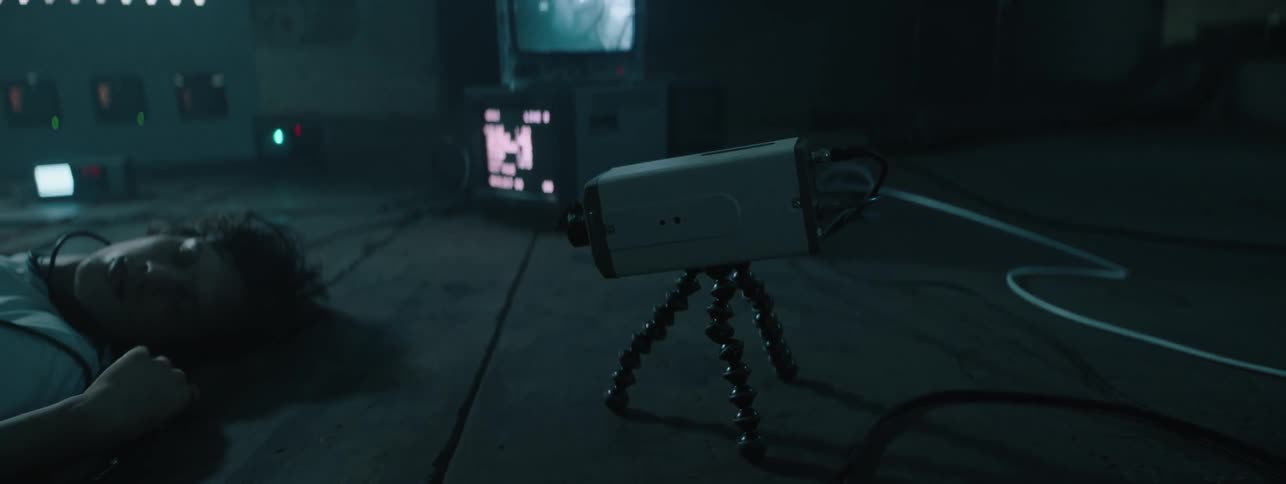 The camera is pointed at a man covered in wires laying on the floor