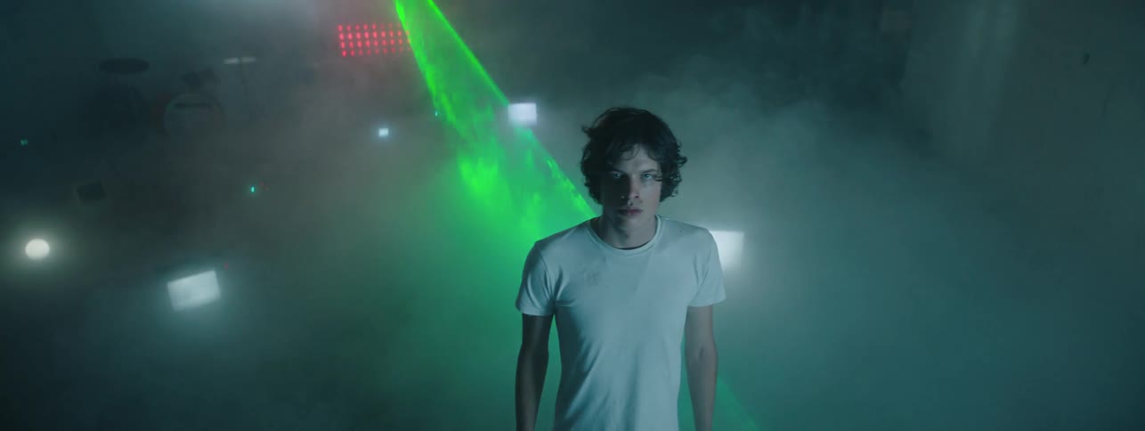 The green light flashes on the man in the foggy room