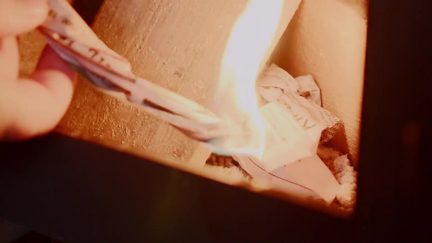A piece of paper is used to light a fire in a wood stove
