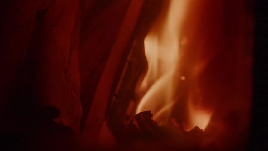 Flames flicker up a piece of wood in a fire at night