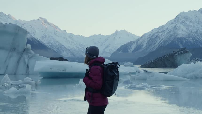 The woman walks near the water on the mountain range