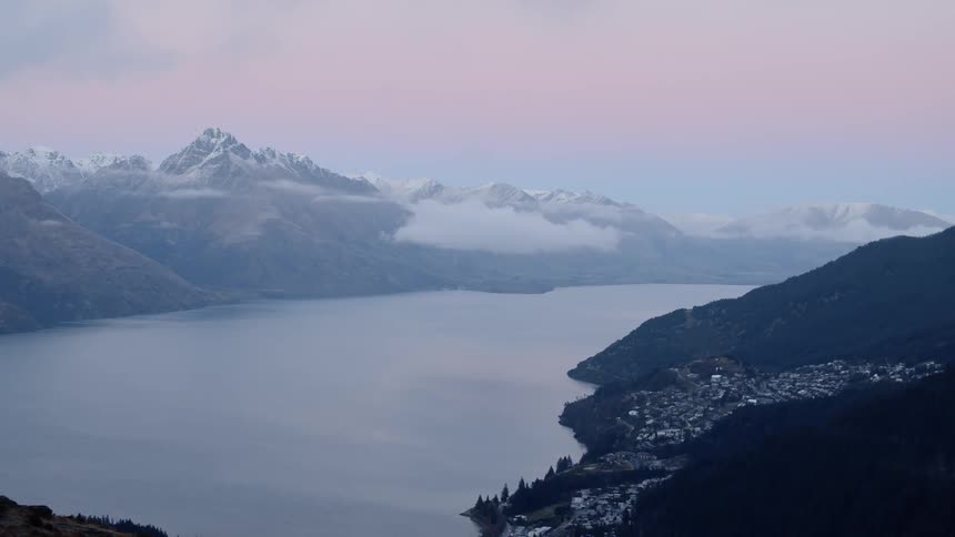 Lake surrounded by snowy mountains on cloudy evening after sunset