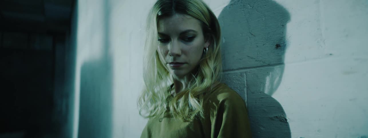 The woman turns her head leaning against the wall