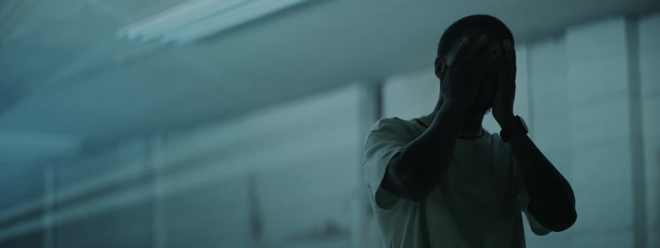 The man wipes his face in the dark room