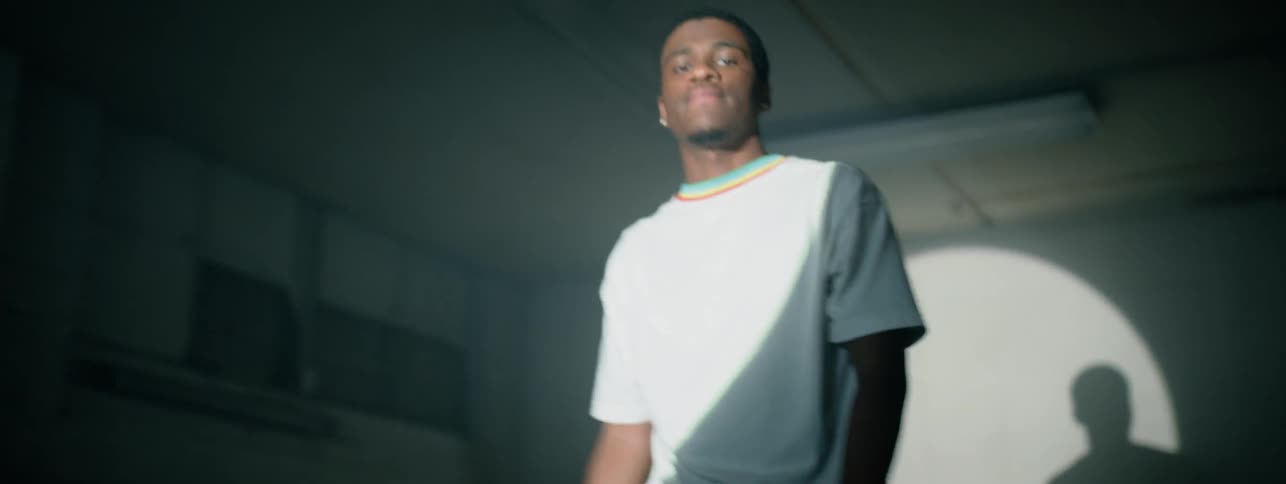 The man wipes his head and moves around in front of the spotlight