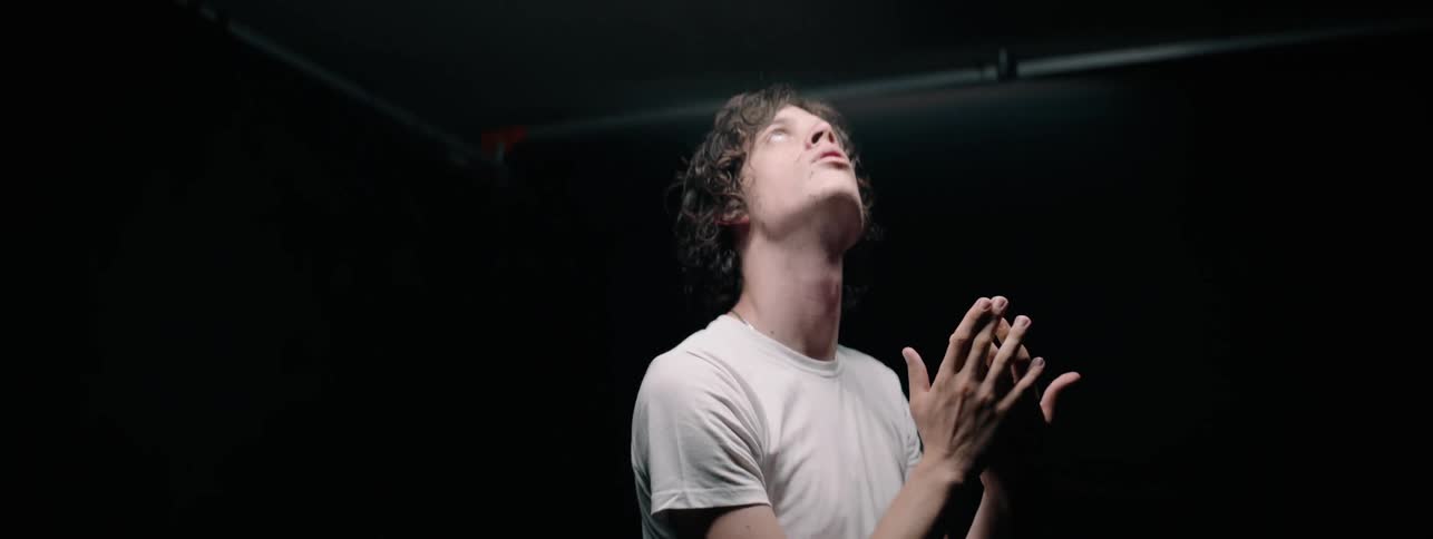 The man looks up at the ceiling in the dark room