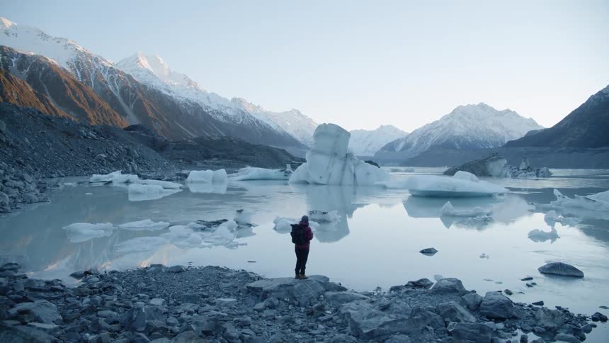 A person stands on the edge of an icy pool of water on a cold day