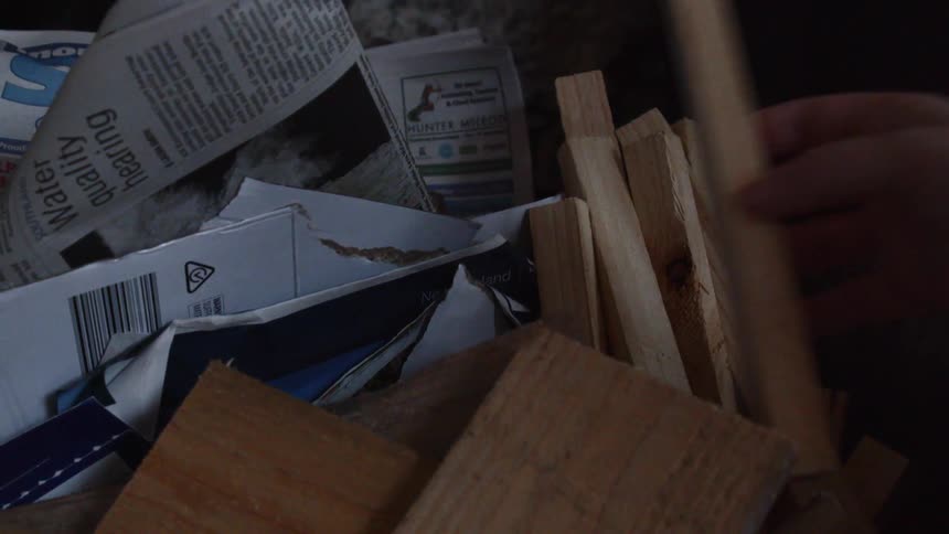 A person picks up kindling from a pile
