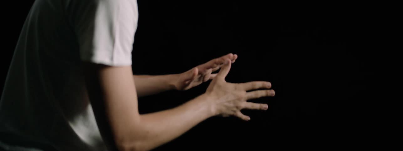 The man looks down at his stretched out hands