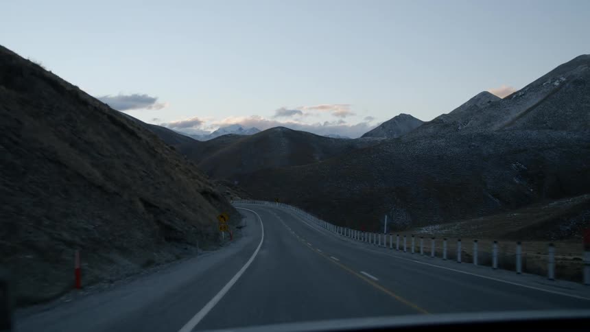 The vehicle travels on the road winding around the mountains