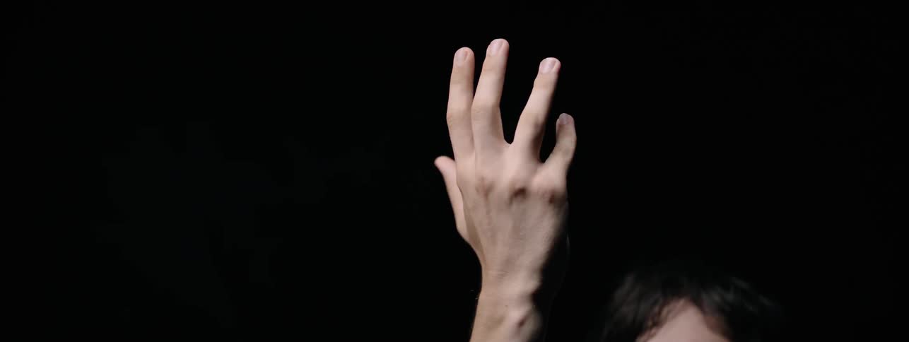 Man with raised arm looks at his hand