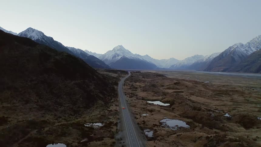 A vehicle travels on the road near the mountain