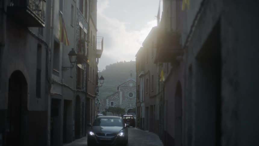 The car drives down the narrow alley