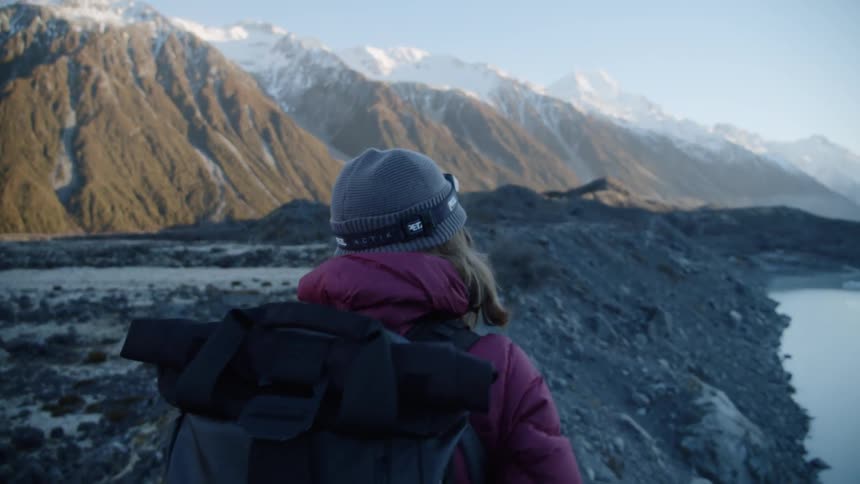 A woman wears a backpack while hiking in snowy mountains