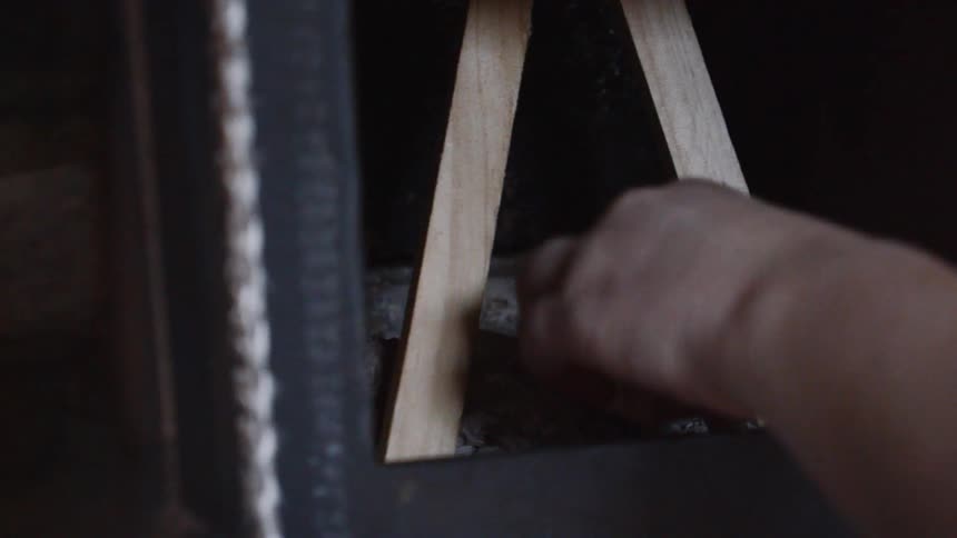 Man places pieces of wood inside a fireplace