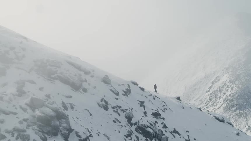 Man stands on the mountainside in foggy