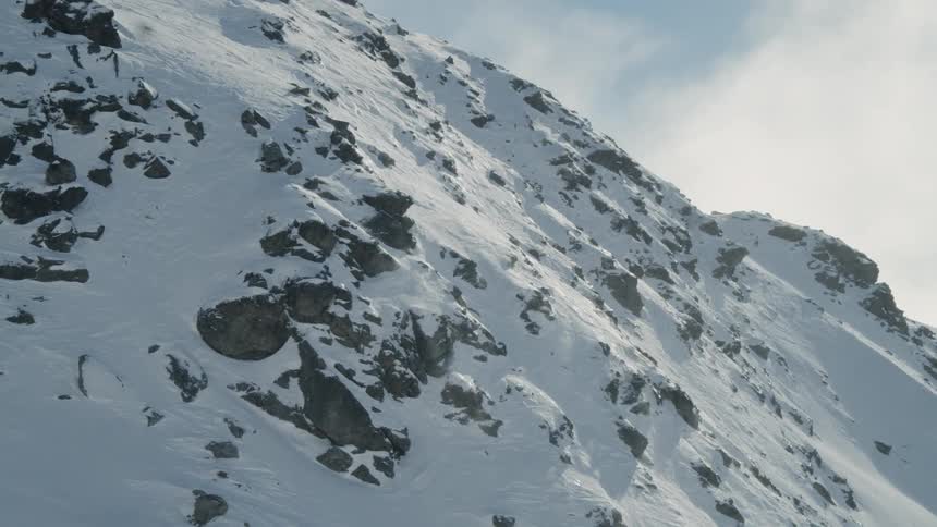 A snowy mountain with rocks poking out of the snow