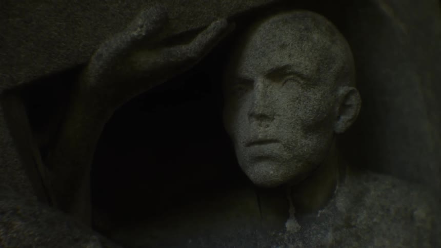 The statue is of a man in a dark area