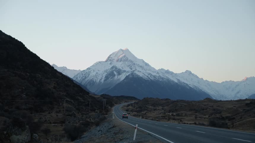 Vehicle travels down a highway and heads towards the snow covered mountains